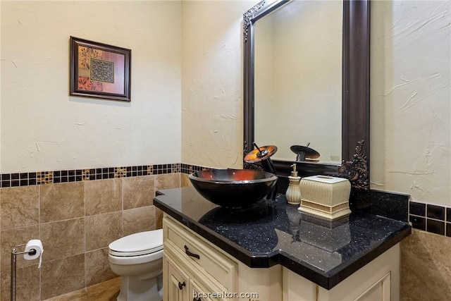 bathroom with vanity, toilet, and tile walls