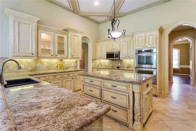 kitchen featuring sink, light stone counters, pendant lighting, a kitchen island, and appliances with stainless steel finishes