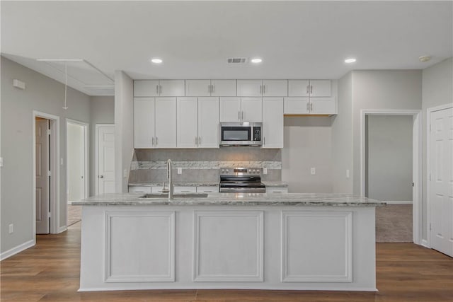 kitchen with sink, white cabinetry, stainless steel appliances, and an island with sink