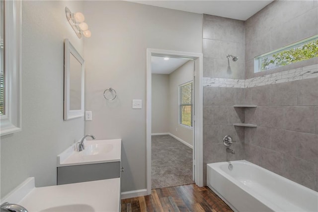 bathroom featuring plenty of natural light, vanity, wood-type flooring, and tiled shower / bath