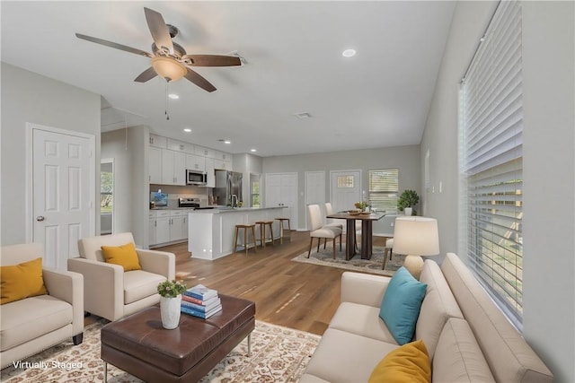 living room featuring light hardwood / wood-style floors, ceiling fan, and a healthy amount of sunlight