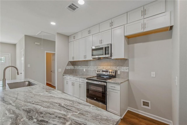 kitchen featuring sink, dark hardwood / wood-style floors, decorative backsplash, white cabinets, and appliances with stainless steel finishes