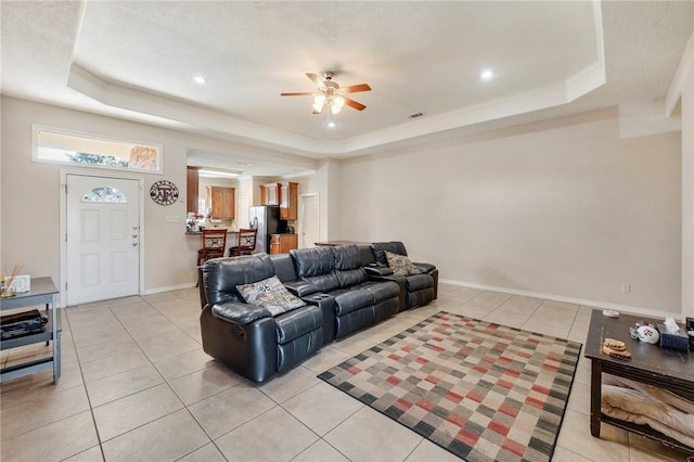 living area with light tile patterned flooring, a raised ceiling, and baseboards