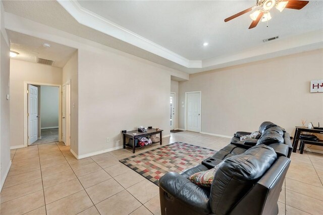 living area with light tile patterned floors, a tray ceiling, visible vents, and baseboards