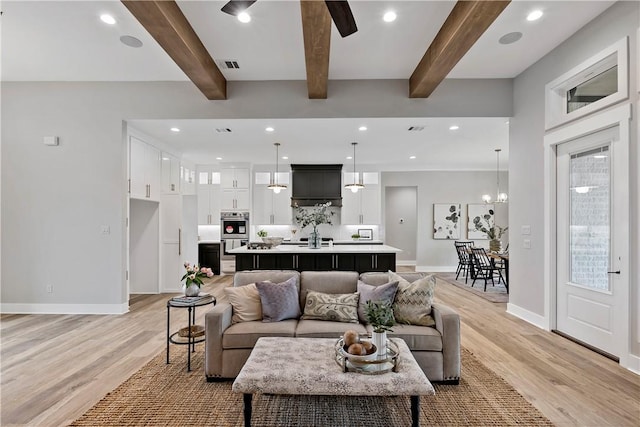 living room with beamed ceiling, a chandelier, and light hardwood / wood-style floors