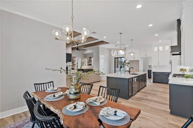 dining room featuring ceiling fan with notable chandelier, sink, and light hardwood / wood-style flooring