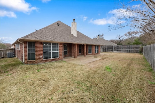 rear view of house featuring brick siding, a chimney, a lawn, a patio area, and a fenced backyard