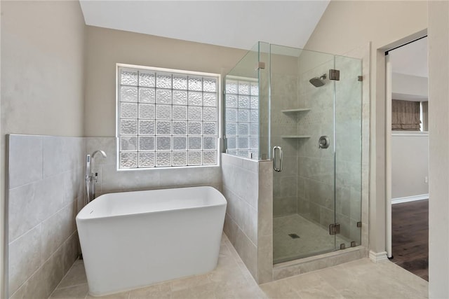 full bathroom featuring tile walls, a freestanding bath, a shower stall, and tile patterned floors