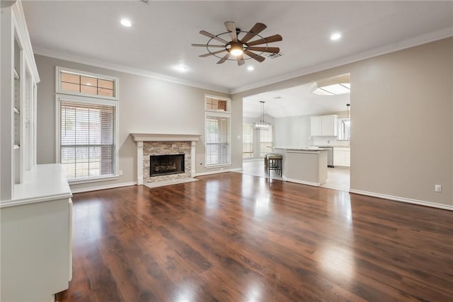 unfurnished living room featuring a fireplace, wood finished floors, a ceiling fan, baseboards, and crown molding