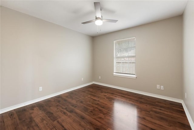 spare room featuring a ceiling fan, dark wood-style flooring, and baseboards