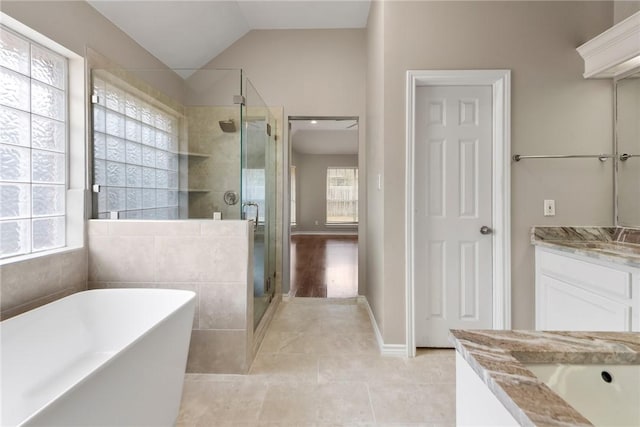 full bathroom featuring lofted ceiling, a shower stall, a freestanding bath, and vanity