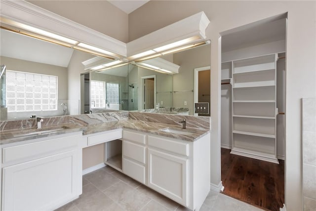 bathroom with a stall shower, tile patterned floors, a sink, and double vanity