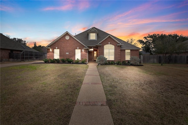 view of front of house with a front yard, brick siding, and fence