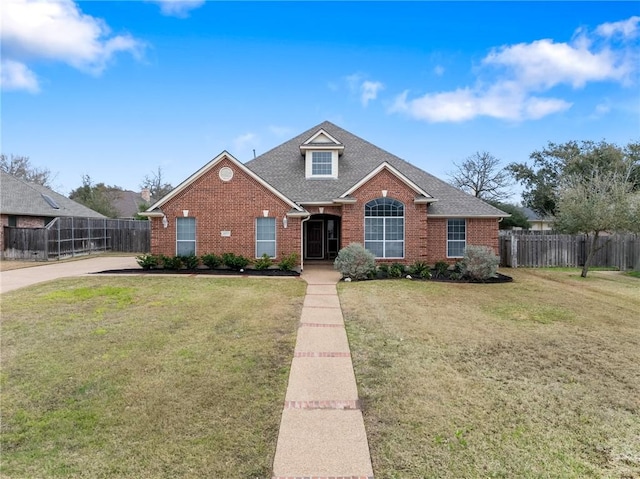 traditional-style house featuring a front yard, fence, roof with shingles, and brick siding