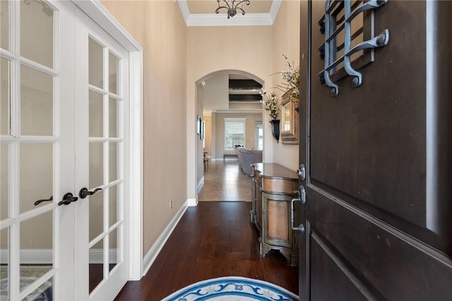 entryway featuring arched walkways, baseboards, french doors, ornamental molding, and dark wood finished floors