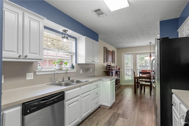 kitchen with hardwood / wood-style floors, decorative light fixtures, white cabinetry, and appliances with stainless steel finishes