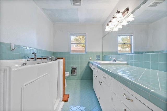 bathroom featuring a wealth of natural light, tile patterned flooring, tile walls, and toilet