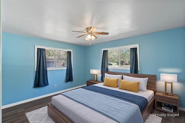 bedroom with dark hardwood / wood-style floors, ceiling fan, and multiple windows