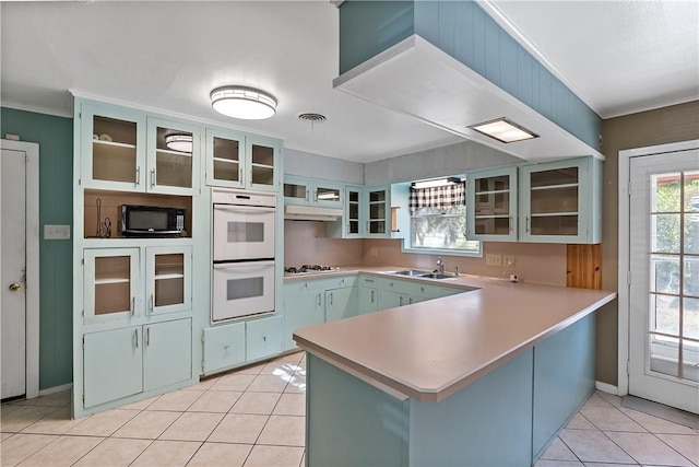 kitchen with sink, kitchen peninsula, crown molding, white appliances, and light tile patterned floors