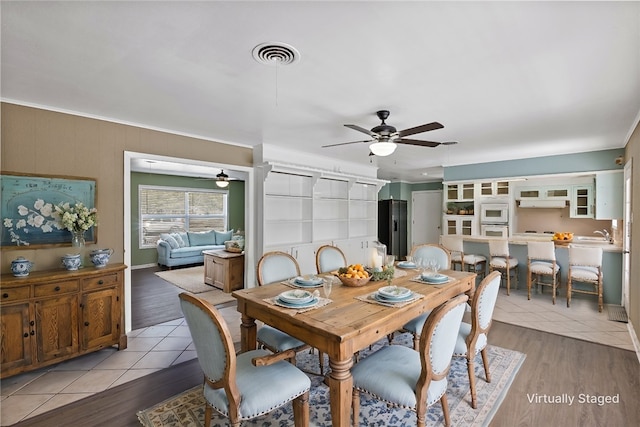 dining area with light hardwood / wood-style flooring, ceiling fan, and sink