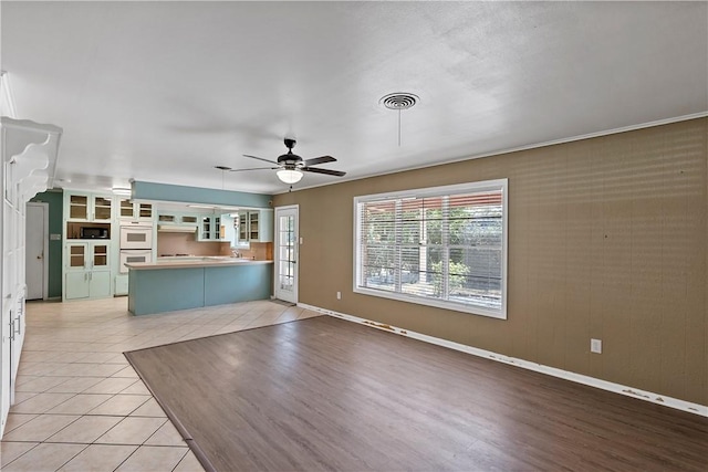 unfurnished living room featuring light hardwood / wood-style floors, ceiling fan, and sink