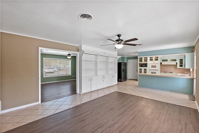 unfurnished living room with ceiling fan, light tile patterned floors, and sink