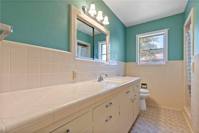 bathroom with a shower with shower curtain, vanity, toilet, and tile walls