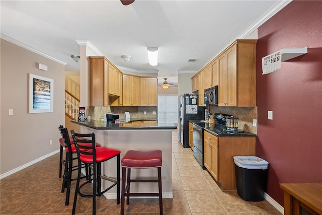 kitchen featuring dark stone countertops, crown molding, decorative backsplash, light tile patterned floors, and black appliances