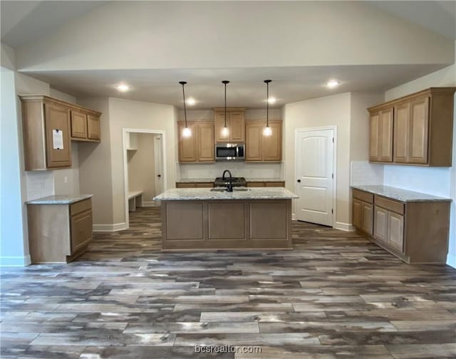 kitchen with pendant lighting, a kitchen island with sink, sink, light stone counters, and dark hardwood / wood-style flooring