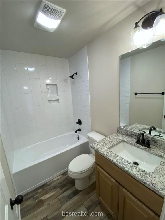 full bathroom with toilet, hardwood / wood-style floors, vanity, and tiled shower / bath