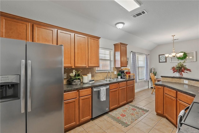 kitchen featuring lofted ceiling, a sink, stainless steel appliances, light tile patterned flooring, and brown cabinetry