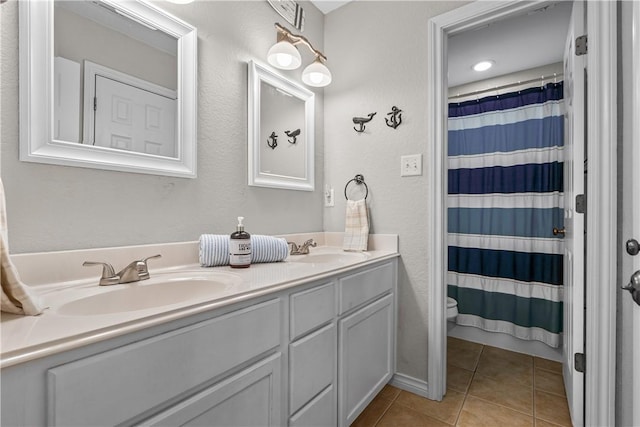 full bath with tile patterned floors, toilet, double vanity, and a sink