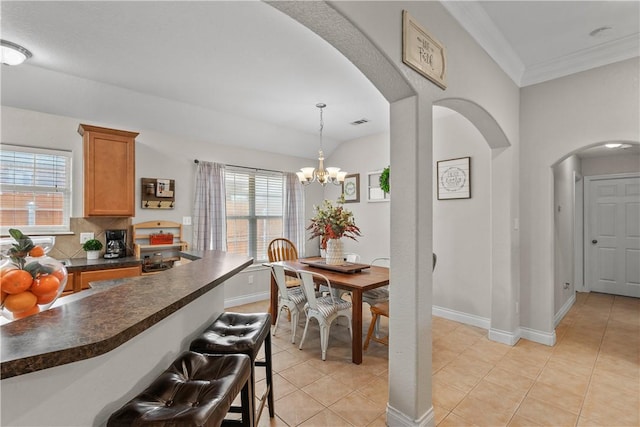 kitchen with light tile patterned floors, a breakfast bar area, baseboards, dark countertops, and arched walkways