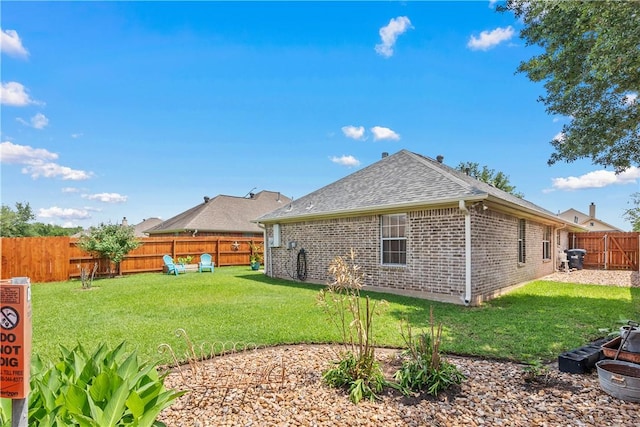 back of property featuring a lawn, a shingled roof, and a fenced backyard