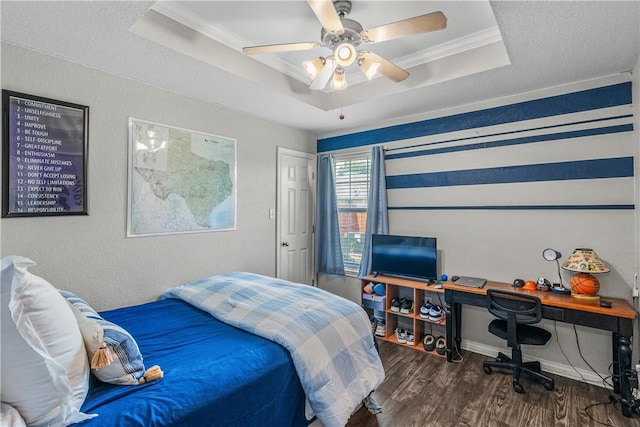 bedroom featuring wood finished floors, a ceiling fan, ornamental molding, and a tray ceiling