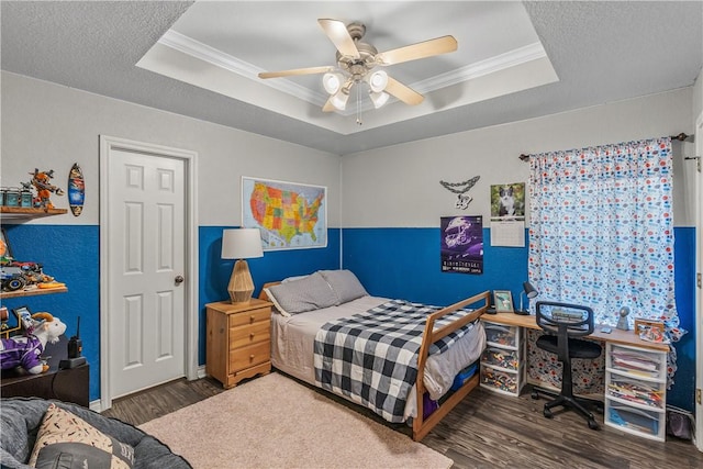 bedroom featuring ornamental molding, ceiling fan, wood finished floors, and a tray ceiling