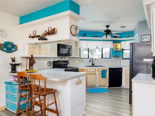 kitchen featuring black appliances, ceiling fan, sink, and light hardwood / wood-style flooring