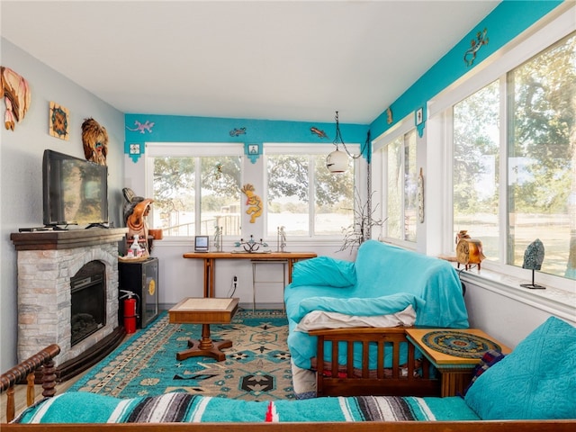 sunroom featuring a stone fireplace and a wealth of natural light