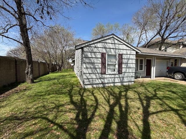 view of side of home with a yard, an attached garage, and fence