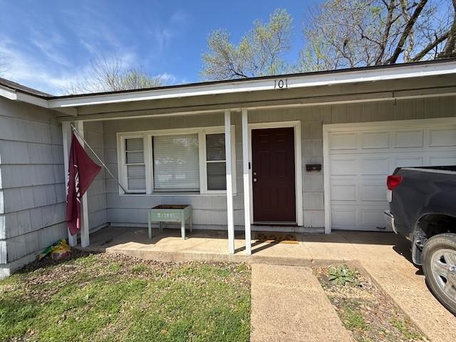 view of exterior entry featuring a porch and an attached garage