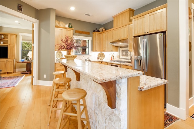18140 Osage Trail Dr, College Station, TX 77845 - kitchen with stainless steel appliances, under cabinet range hood, light brown cabinets, light wood finished floors, and recessed lighting