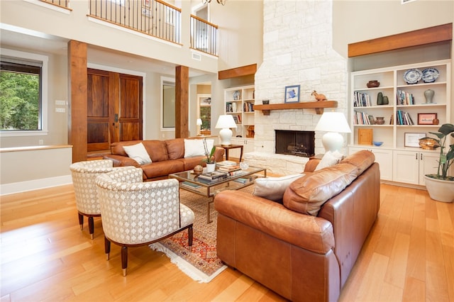 18140 Osage Trail Dr, College Station, TX 77845 - living area with light wood-style floors, a high ceiling, built in features, a stone fireplace, and baseboards