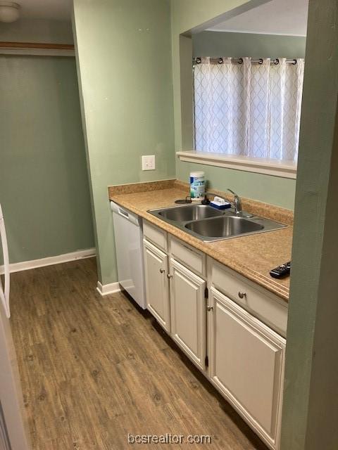 kitchen featuring dishwasher, white cabinetry, dark wood-type flooring, and sink