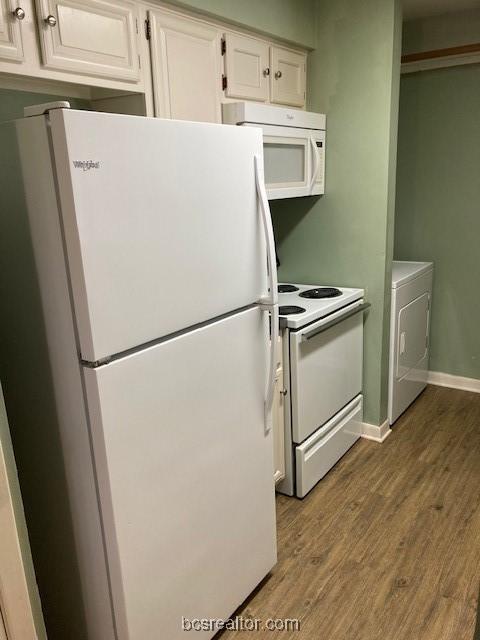 kitchen featuring hardwood / wood-style floors, white cabinetry, white appliances, and washer / clothes dryer