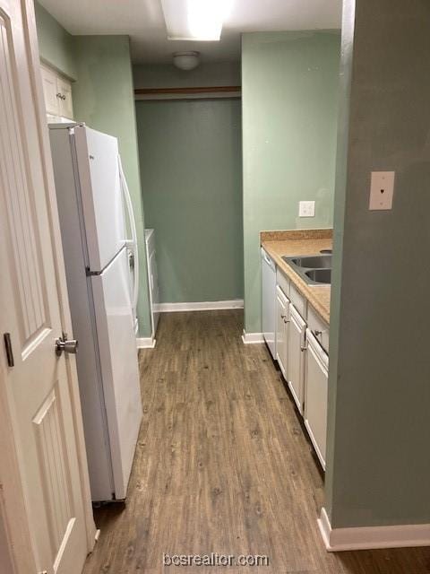 kitchen with dark hardwood / wood-style flooring, white appliances, white cabinetry, and sink