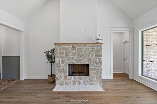 2160 Madden Cir, College Station, TX 77845 - unfurnished living room featuring high vaulted ceiling, a stone fireplace, wood finished floors, and baseboards