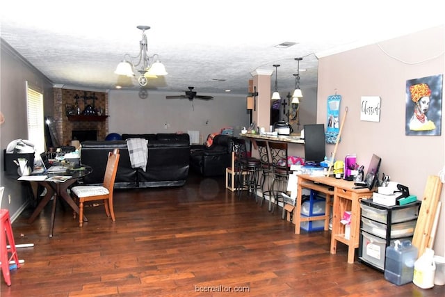 dining area with a fireplace, dark hardwood / wood-style flooring, ceiling fan with notable chandelier, and ornamental molding