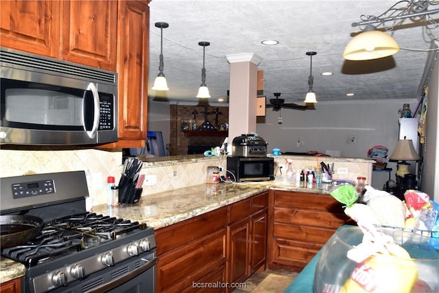 kitchen featuring pendant lighting, light stone counters, ornamental molding, and stainless steel appliances