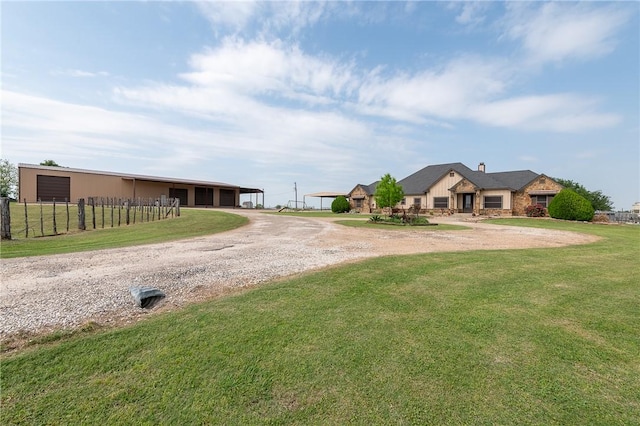 view of front of home with driveway, a chimney, a detached garage, fence, and a front lawn
