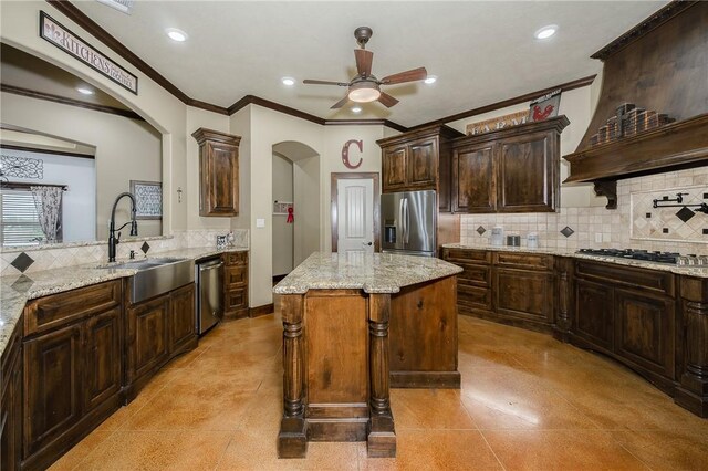 kitchen with ceiling fan, appliances with stainless steel finishes, arched walkways, tasteful backsplash, and a sink